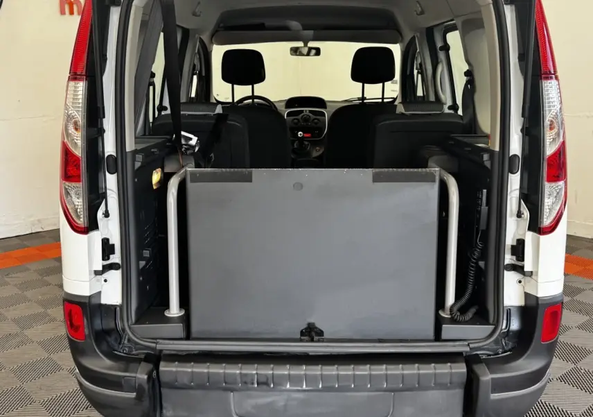 Vue arrière ouverte du Renault Kangoo blanc 2016, montrant l'intérieur et une barrière de sécurité grise dans le coffre.