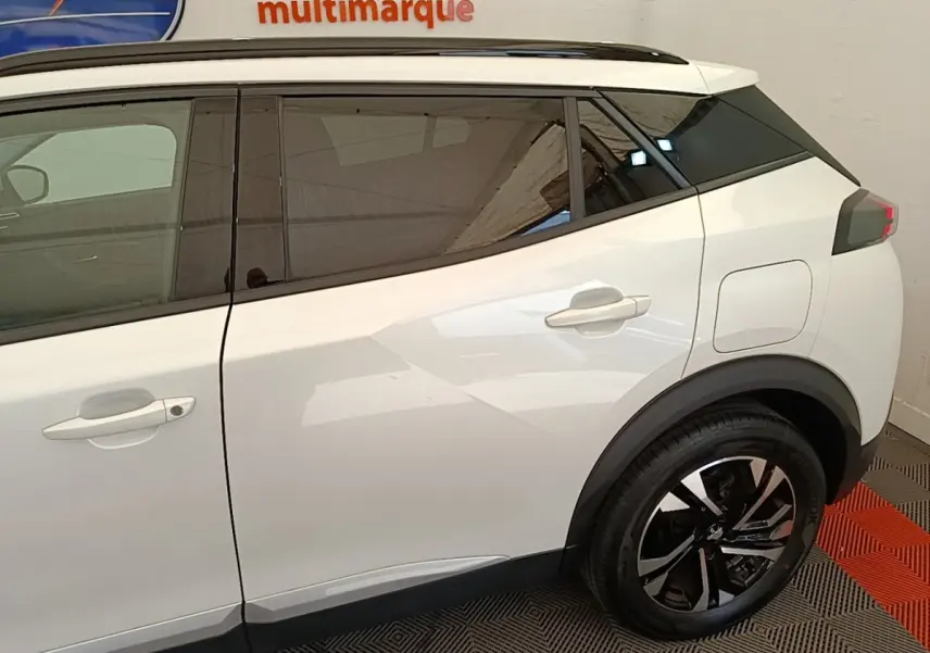 Vue latérale droite d'un Peugeot 2008 blanc avec jantes alliage noires et vitres teintées.