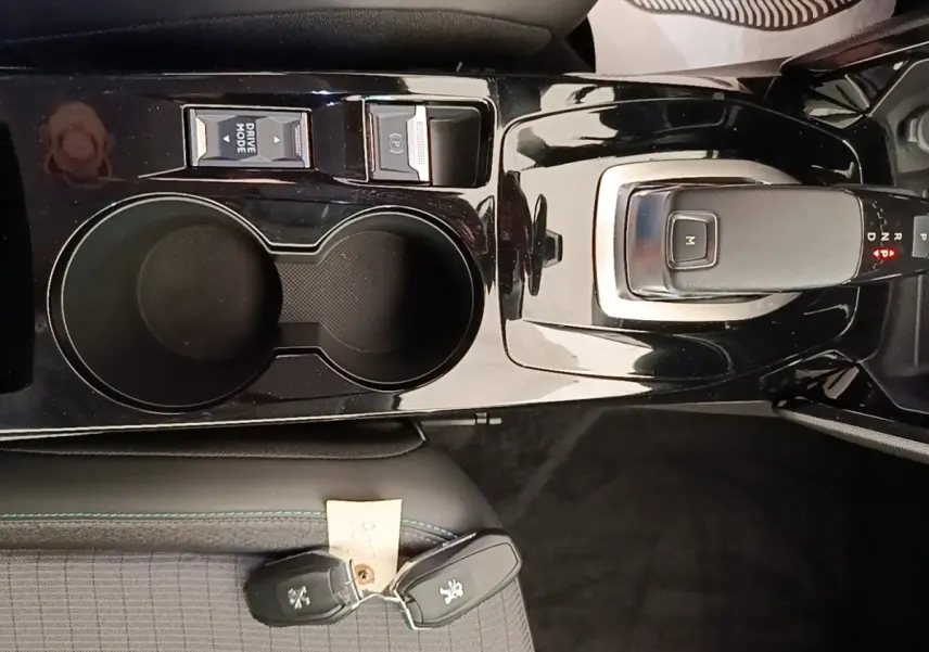 Vue rapprochée de la console centrale noire brillante avec levier de vitesse automatique et porte-gobelets du Peugeot 2008 blanc.