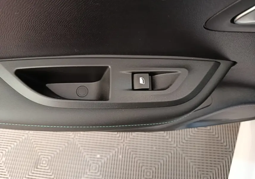 Poignée intérieure de porte côté droit du Peugeot 2008 blanc, avec bouton de verrouillage et surpiqûres bleues.