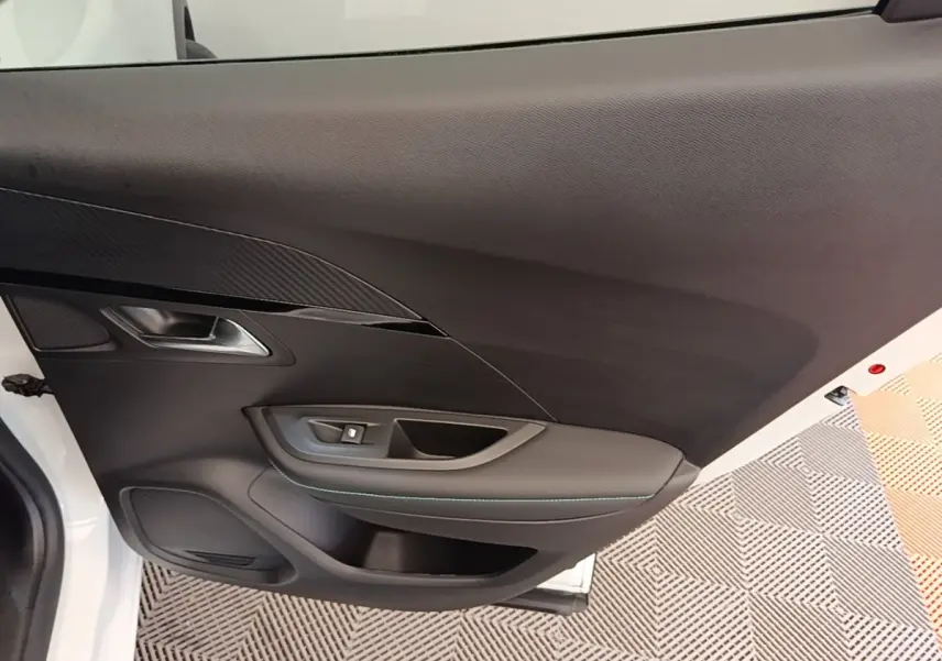 Vue intérieure sur la porte avant gauche noire d’un Peugeot 2008 blanc, avec poignée et commande de vitre.