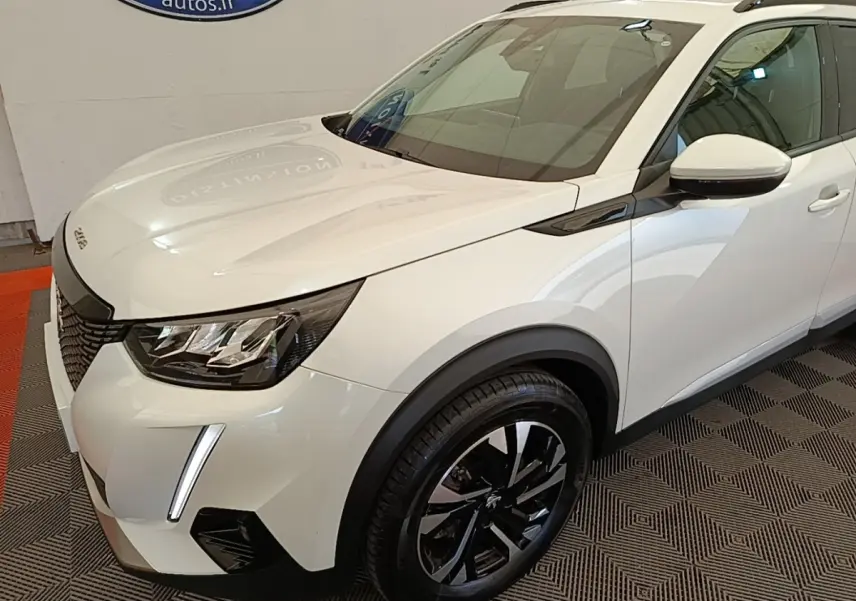 Vue 3/4 avant droit d’un Peugeot 2008 blanc avec phares LED et jantes alliage noires brillantes.