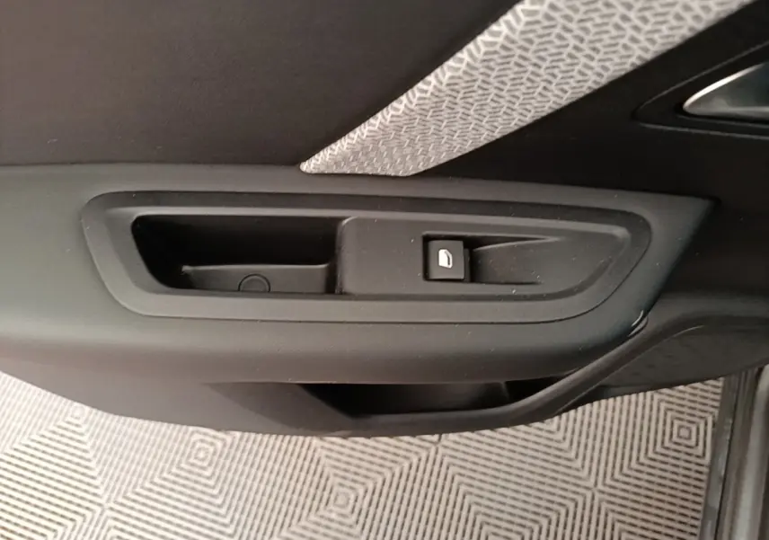 Gros plan sur la poignée intérieure de porte côté droit d’une Citroën C4 gris clair, avec bouton de verrouillage.