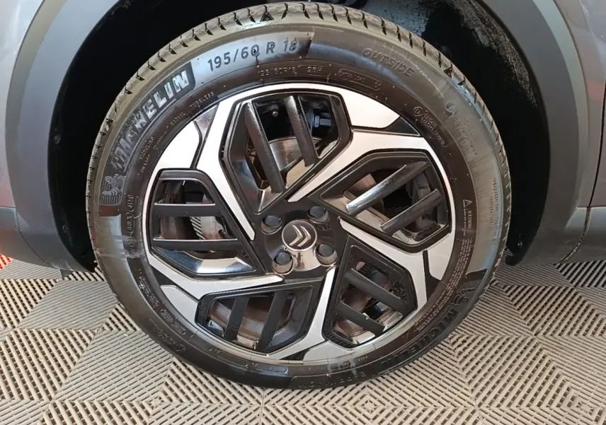 Gros plan sur la roue avant droite d’une Citroën C4 gris clair avec jante alliage au design géométrique noir et argent.