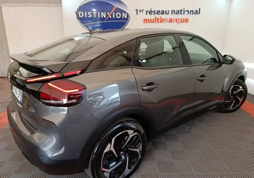 Vue 3/4 arrière droite d'une Citroën C4 gris clair avec feux LED et jantes noires au design moderne.