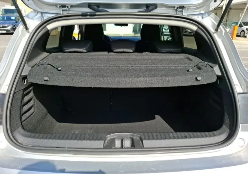 Coffre ouvert vu de l'arrière d'une Renault Clio 1.6 E-Tech gris platine, montrant la plage arrière et l'espace de chargement.