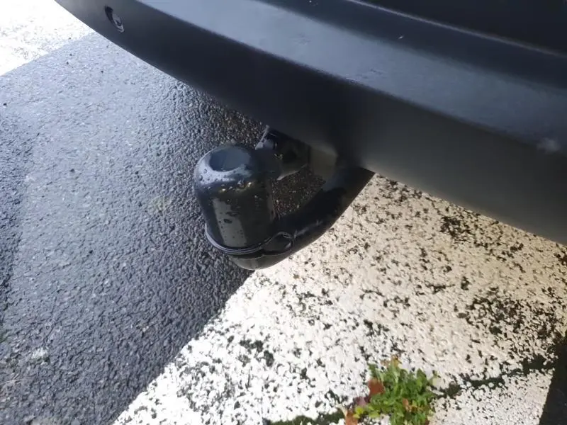 Gros plan sur l'attelage de remorque noir sous le pare-chocs arrière du KIA SPORTAGE blanc 2013.