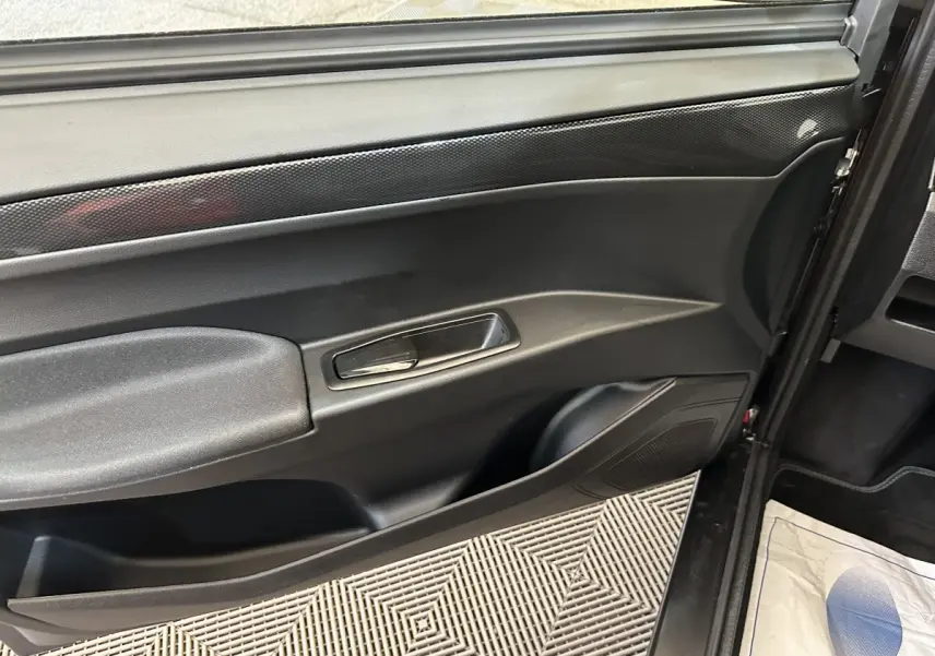 Vue intérieure du panneau de porte côté conducteur d'une Aixam Ambition rouge, avec poignée argentée et finition noire.