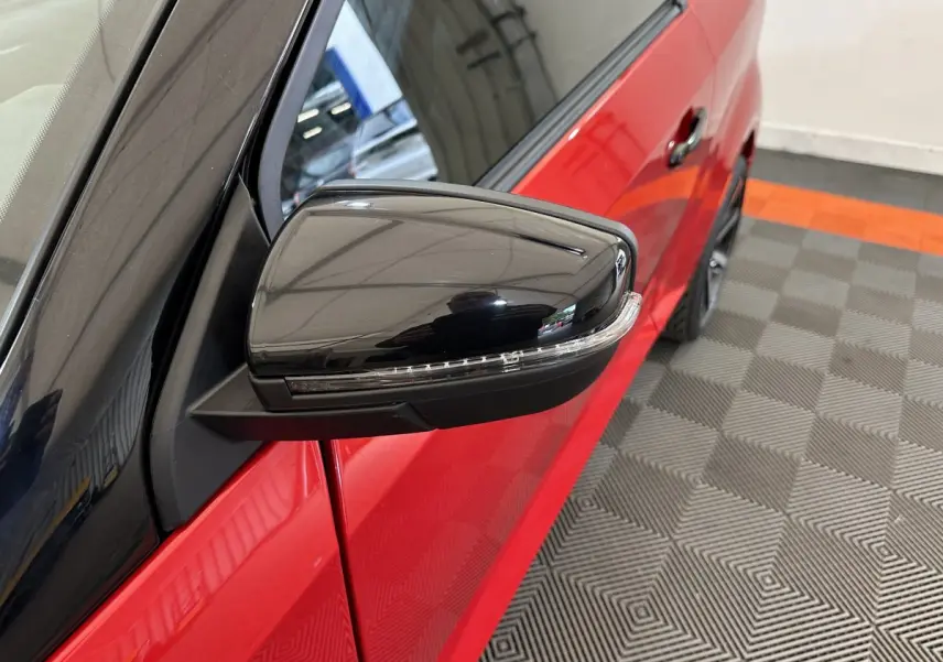 Gros plan sur le rétroviseur extérieur noir côté conducteur d'une Aixam Ambition rouge 2026, avec caméra intégrée.