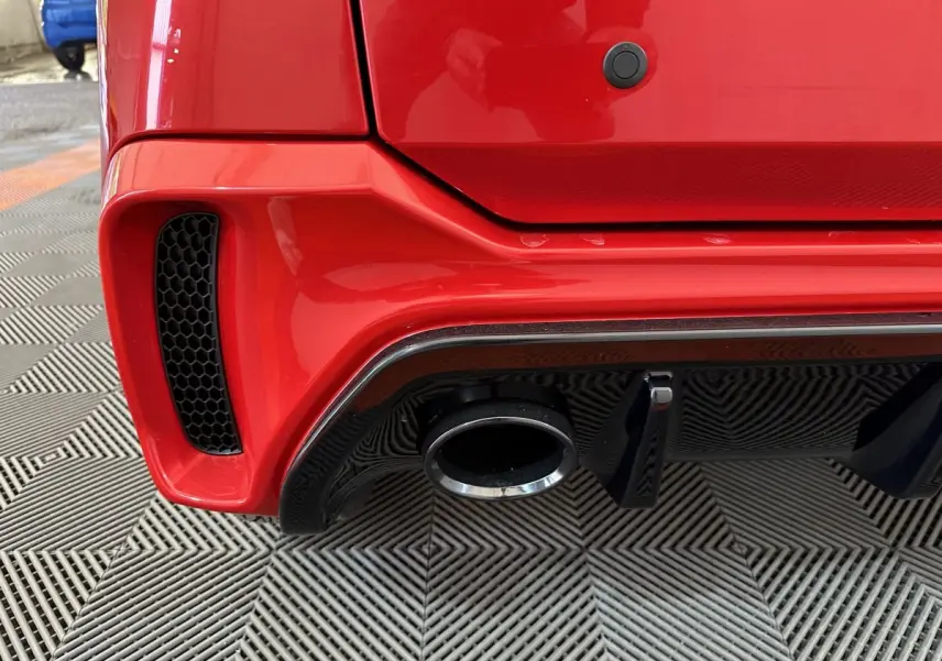 Gros plan sur l’échappement et le diffuseur arrière noir d’une Aixam Ambition rouge, vue arrière côté droit.