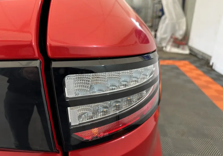 Gros plan sur le feu arrière droit rouge de l'AIXAM AMBITION 0.5 CITY COUPE GTI E5+ 2026 dans un garage.