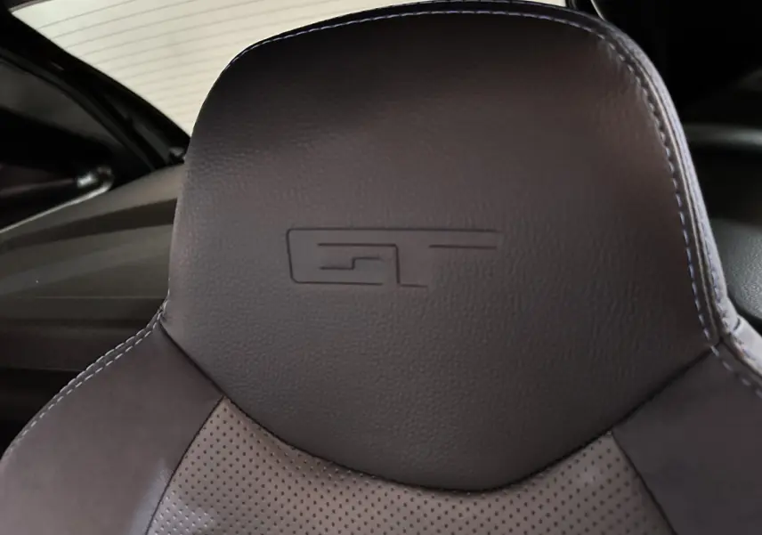Gros plan sur l'appui-tête en cuir noir avec logo GT embossé, intérieur de l'AIXAM AMBITION 0.5 CITY COUPE GTI 2026.