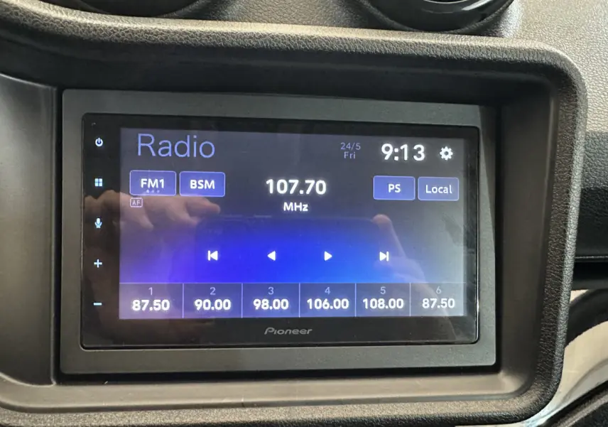 Écran radio Pioneer affichant la fréquence 107.70 MHz dans l'habitacle de l'AIXAM Ambition rouge, vue de face.