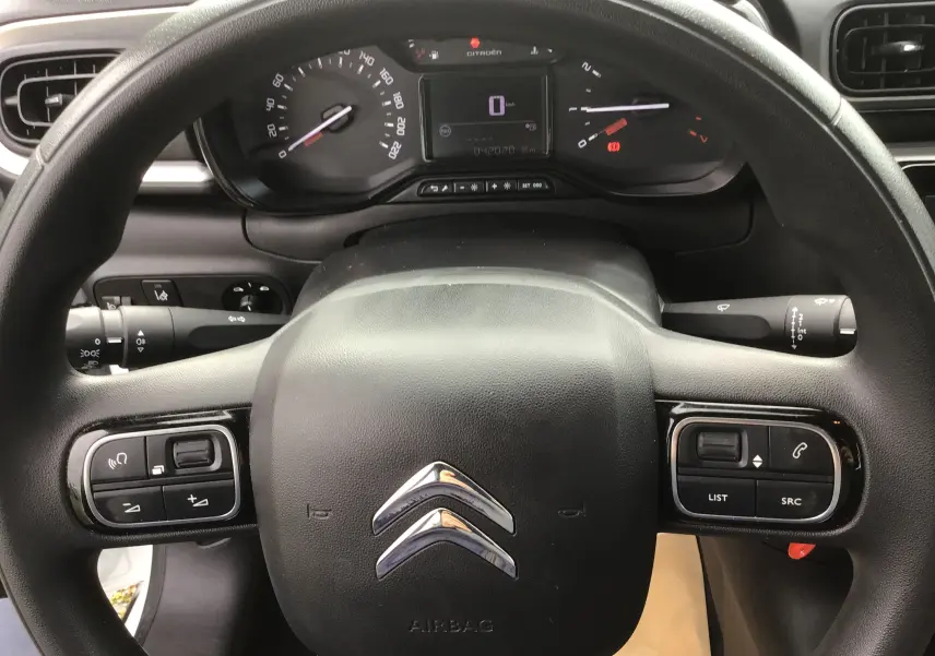 Vue rapprochée du volant noir avec logo Citroën et tableau de bord numérique d'une C3 blanche essence 2021.