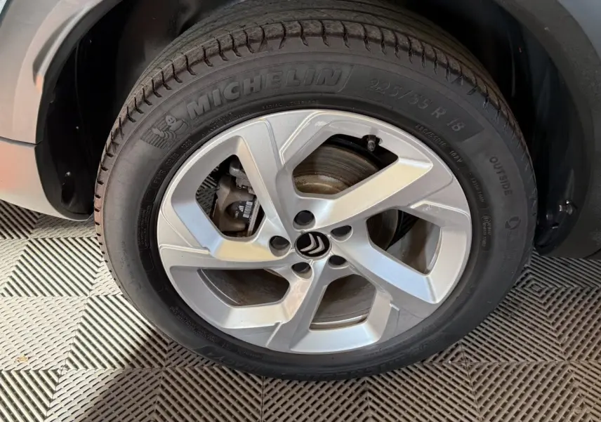 Gros plan sur la roue avant gauche avec jante argentée et pneu Michelin du Citroën C5 Aircross bleu hybride.