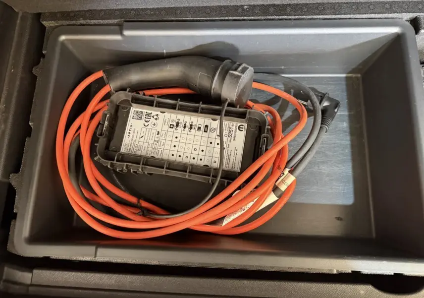 Câble de recharge hybride rouge et noir rangé dans le coffre d’un Citroën C5 Aircross bleu, vue de dessus.
