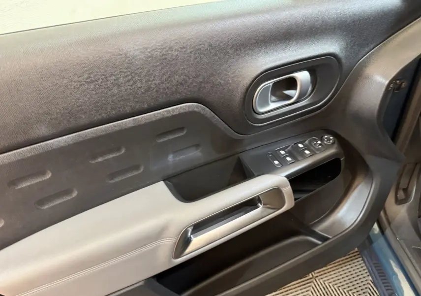 Détail de la porte avant gauche du Citroën C5 Aircross Hybrid bleu, avec commandes électriques et poignée argentée.