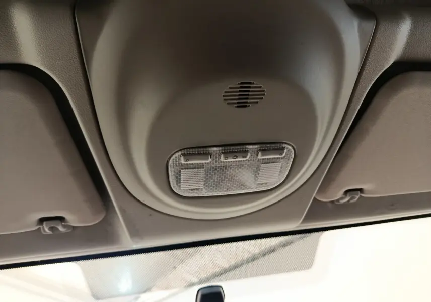 Plafonnier intérieur beige avec commandes d’éclairage, vue en contre-plongée depuis l’avant du Peugeot Partner blanc.