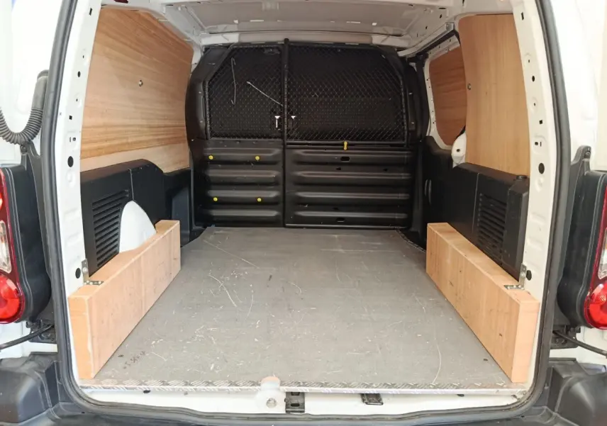 Vue arrière du coffre blanc du Peugeot Partner 1.6 BlueHDi 100 Long Pro avec cloison tubulaire et aménagement bois.