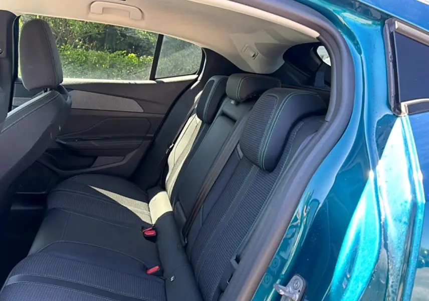 Vue côté gauche sur l’arrière d’une Peugeot 408 Hybrid 145 allure e-dcs6 bleu, montrant la banquette arrière en tissu et cuir.