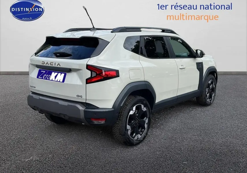 Vue 3/4 arrière droite du Dacia Duster 2025 Sandstone avec jantes alu et barres de toit noires.