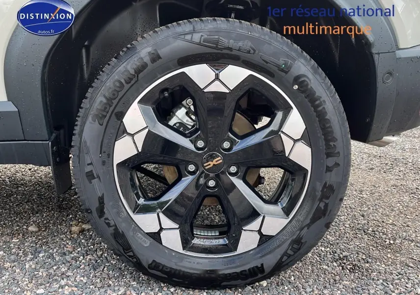 Gros plan sur la roue avant droite du Dacia Duster 2025 Sandstone avec jante alu bicolore et pneu Continental.