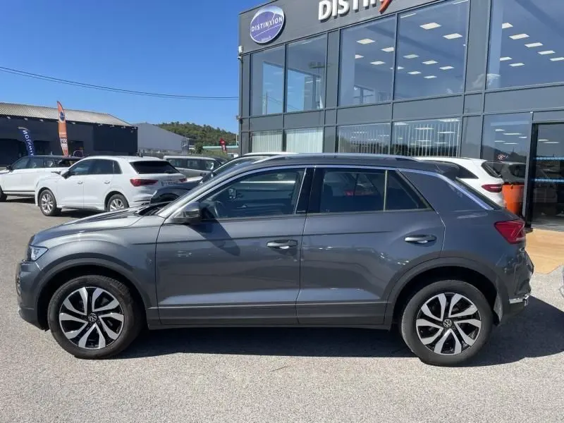 Volkswagen T-Roc 1.5 TSI 150 Active DSG7 gris foncé métal vu de profil côté gauche, roues alliage distinctives visibles.