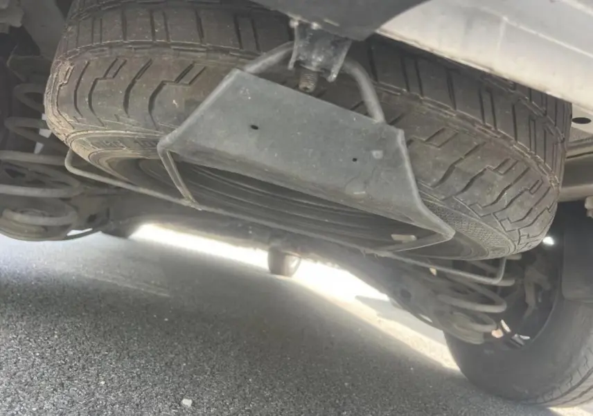 Gros plan sous le Citroën Jumpy blanc montrant la roue de secours suspendue et la suspension arrière.