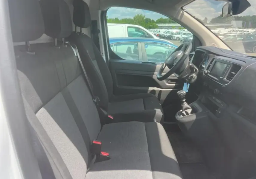 Vue intérieure côté conducteur du Citroën Jumpy XL blanc, montrant les sièges tissu bi-ton et le tableau de bord avec écran tactile.