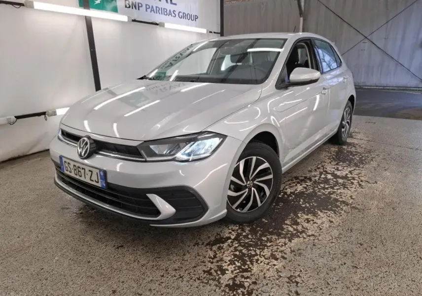 Volkswagen Polo gris clair vue 3/4 avant droit, phares LED allumés et jantes alliage distinctives.