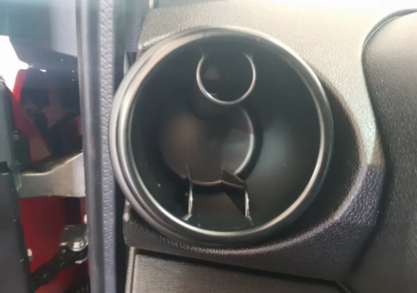 Gros plan sur la sortie d’air intérieure du tableau de bord, avec partie rouge visible côté gauche du véhicule.
