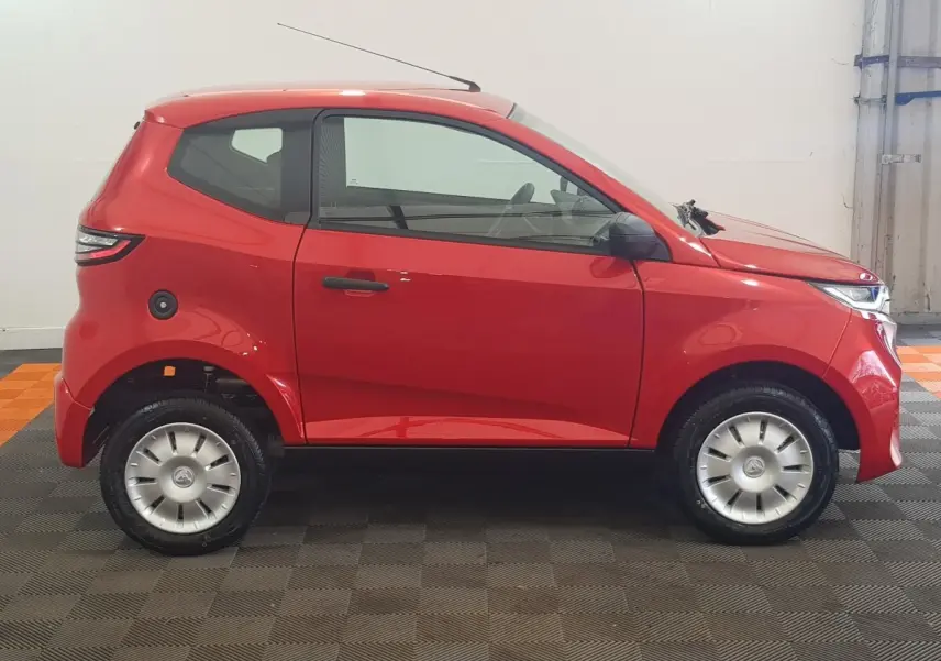 Vue de profil côté gauche d'une Aixam Ambition 0.5 City Pack rouge avec rétroviseur caméra côté conducteur.
