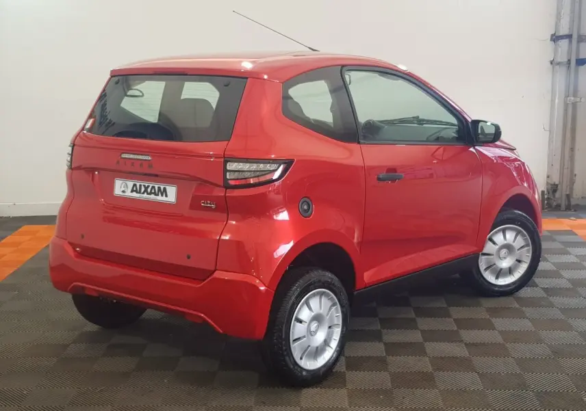 Vue 3/4 arrière droite d'une Aixam Ambition 0.5 City Pack rouge avec rétroviseur caméra côté conducteur.
