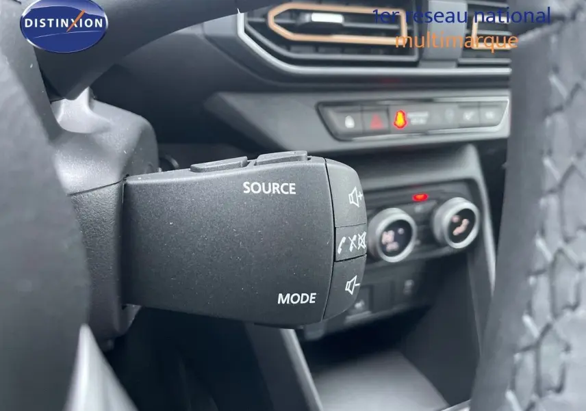 Commande au volant avec boutons source et mode, tableau de bord et commandes de climatisation du Dacia Sandero Stepway 2024.
