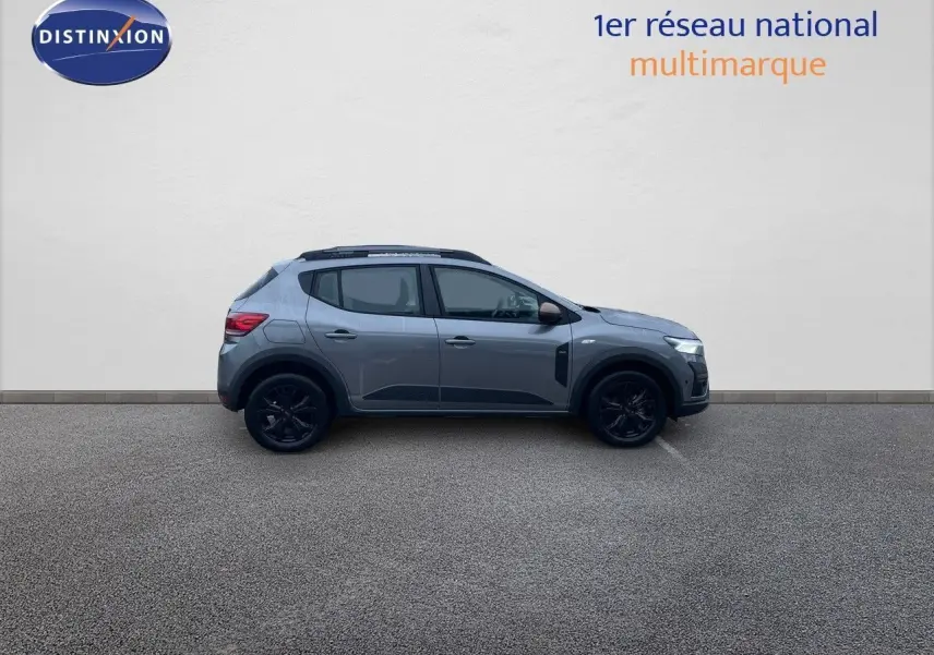 Profil côté gauche d'une Dacia Sandero Stepway 2024 gris schiste métal avec jantes noires et rétroviseurs bronze.