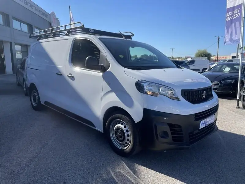 Peugeot Expert Fourgon blanc vu en 3/4 avant droit avec galerie de toit et pare-chocs noirs, stationné en extérieur.