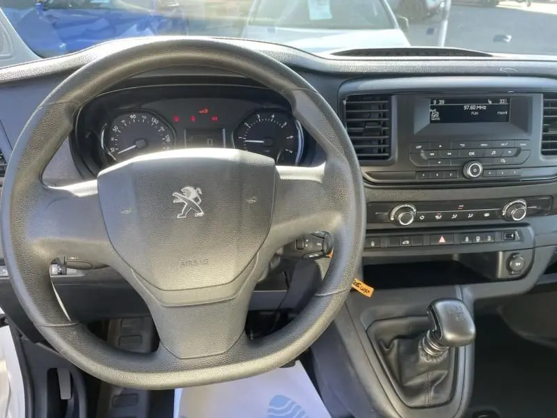 Vue intérieure centrée sur le volant Peugeot d'un Expert Fourgon blanc 2023 avec tableau de bord et levier de vitesse manuel.
