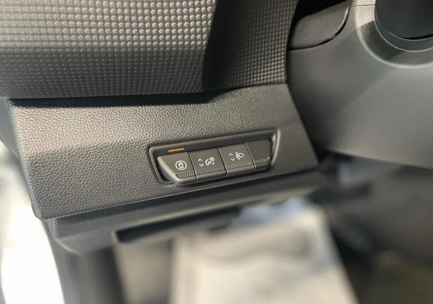 Gros plan sur les commandes de réglage d'éclairage et verrouillage dans l'habitacle du Renault Trafic Fourgon blanc.