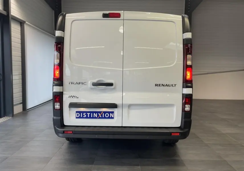 Vue arrière du Renault Trafic Fourgon blanc avec feux allumés et plaque Distinxion dans un garage.