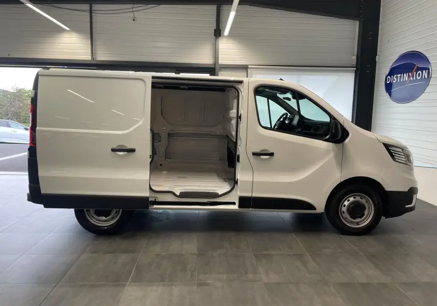 Renault Trafic Fourgon blanc en vue profil droit avec porte latérale coulissante ouverte montrant l'espace de chargement vide.