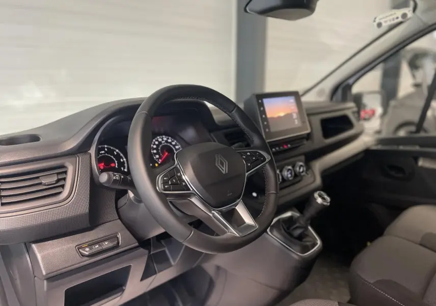 Vue intérieure du poste de conduite du Renault Trafic Fourgon blanc, avec volant multifonction et écran tactile central.