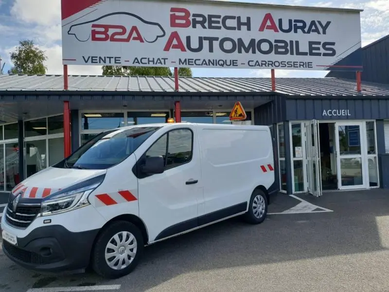 Renault Trafic Fourgon blanc glacier vu en 3/4 avant droit, équipé de bandes réfléchissantes rouges sur la carrosserie.