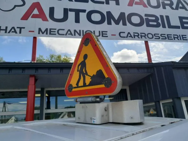Panneau triangulaire de chantier jaune et rouge fixé sur le toit blanc d'un Renault Trafic Fourgon L1H1 2019 vu de dessus