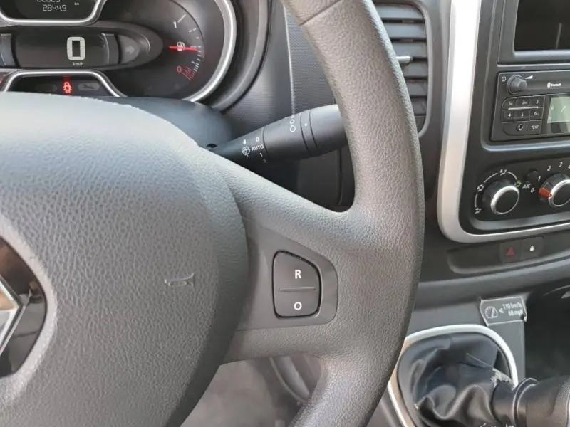Vue rapprochée de l'intérieur du Renault Trafic Fourgon blanc, montrant le volant, tableau de bord et commandes centrales.