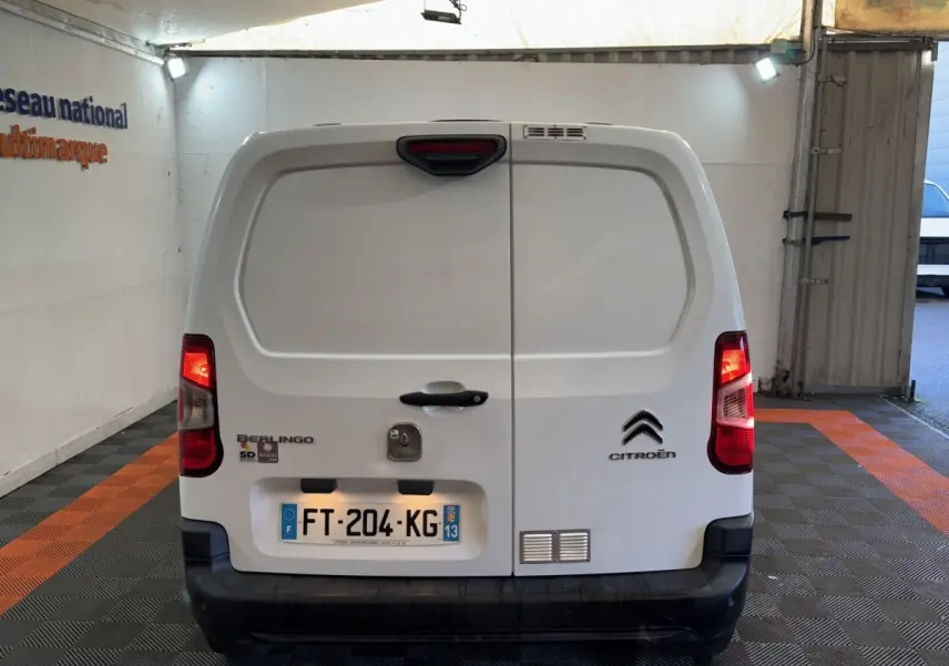 Vue arrière d’un utilitaire Citroën Berlingo blanc avec portes battantes fermées et feux arrière allumés.