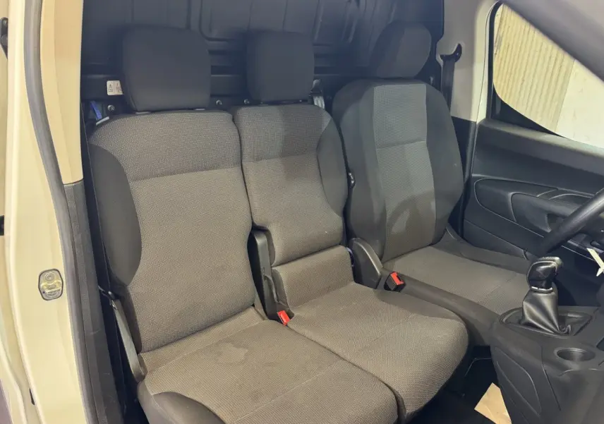 Vue intérieure côté conducteur du Citroën Berlingo blanc 2020 montrant les sièges avant gris et la boîte manuelle.