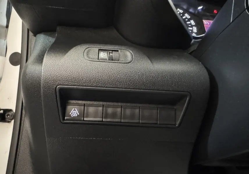 Vue rapprochée du tableau de bord côté conducteur du Citroën Berlingo blanc, avec commande d'éclairage et bouton d'assistance désactivée.