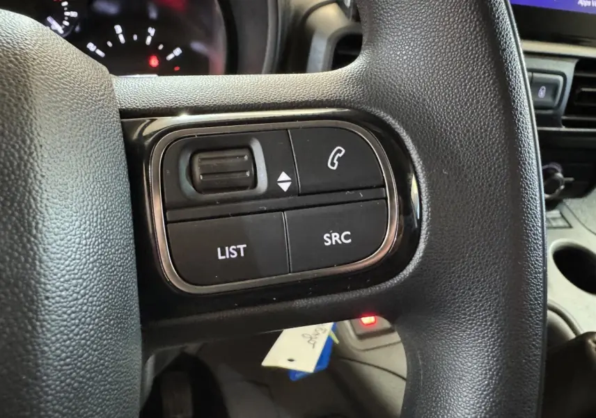 Gros plan sur les commandes multifonctions noires du volant du Citroën Berlingo 2020, intérieur gris.