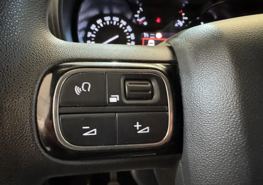 Gros plan sur les commandes multifonctions noires du volant du Citroën Berlingo 2020, avec tableau de bord en arrière-plan.