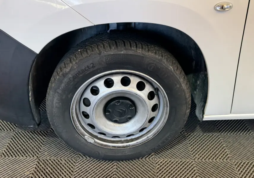 Gros plan sur la roue avant gauche d’un Citroën Berlingo blanc avec jante acier et logo Citroën au centre.
